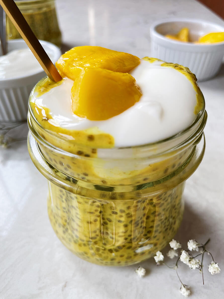 golden turmeric chia seed pudding recipe in a mason jar with yogurt and mango on top
