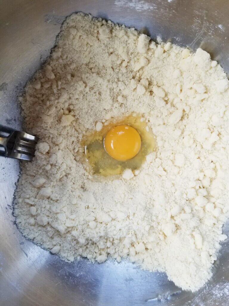 adding the egg to the pie crust dough