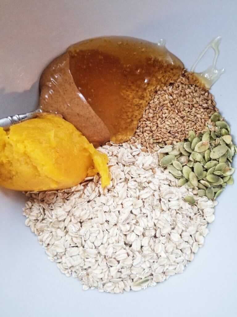 old fashioned oats, pumpkin seeds, flax seeds, pumpkin puree, almond butter, and maple syrup in a bowl
