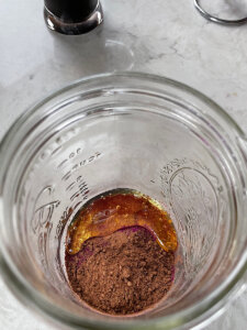 pink pitaya powder cacao powder and honey in a glass