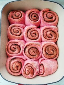 pink cinnamon rolls in pan after baking
