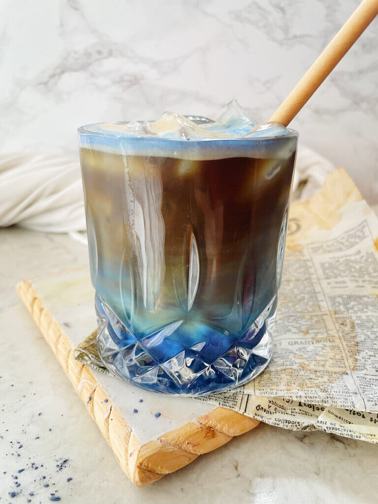 Splash of iced coffee in tall glass and coffee beans. Stock Photo