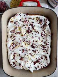 rose milk cake topped with dried rose petals and crushed pistachio