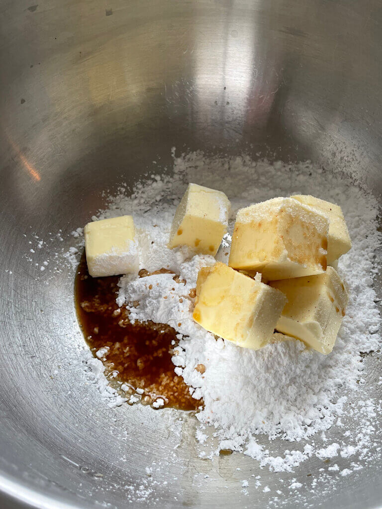 butter and powdered sugar in a mixing bowl with vanilla extract